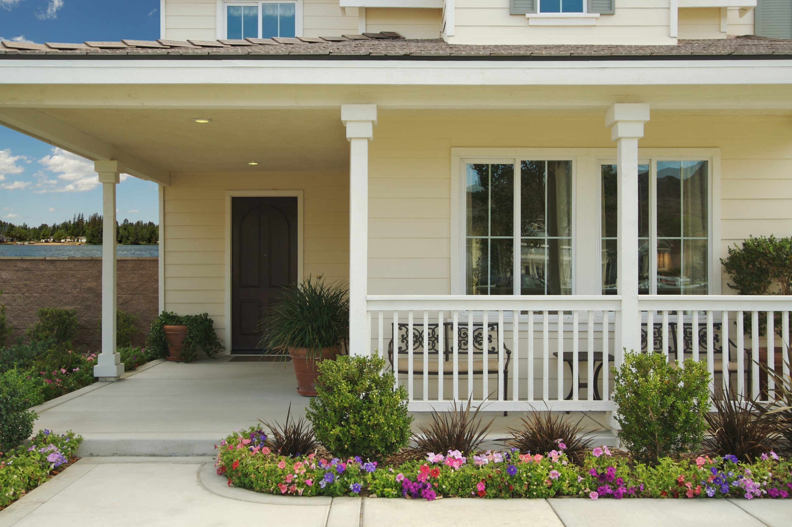 American flag displayed on front porch surrounded by white hydrangea flowers