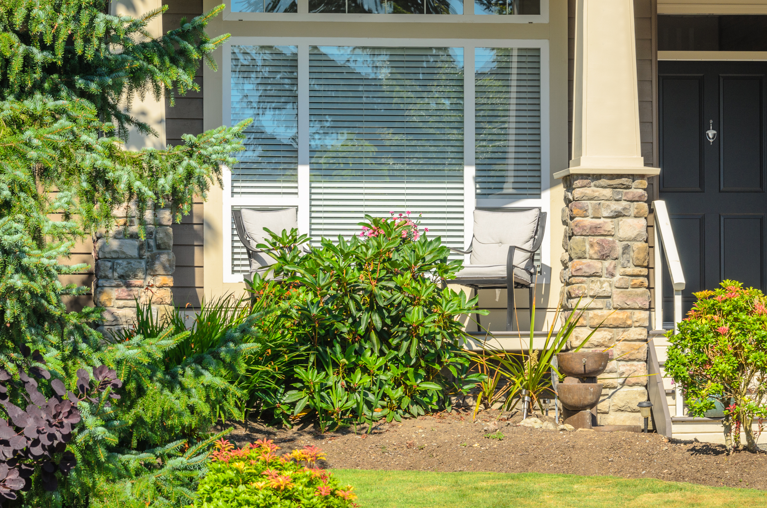 Beautiful American front porch with hanging flower baskets, white chairs and hydrangea garden