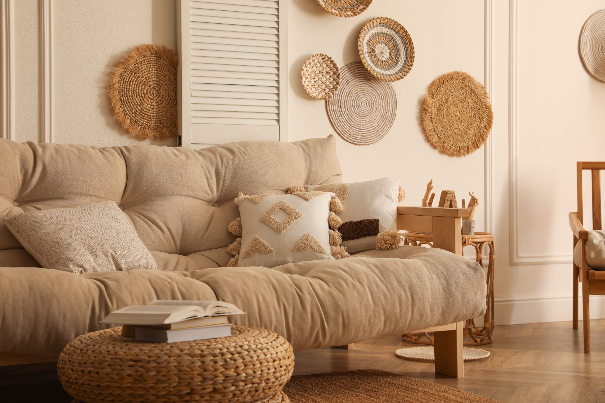 Boho americana living room corner with rattan wall baskets, beige sofa and woven pouf