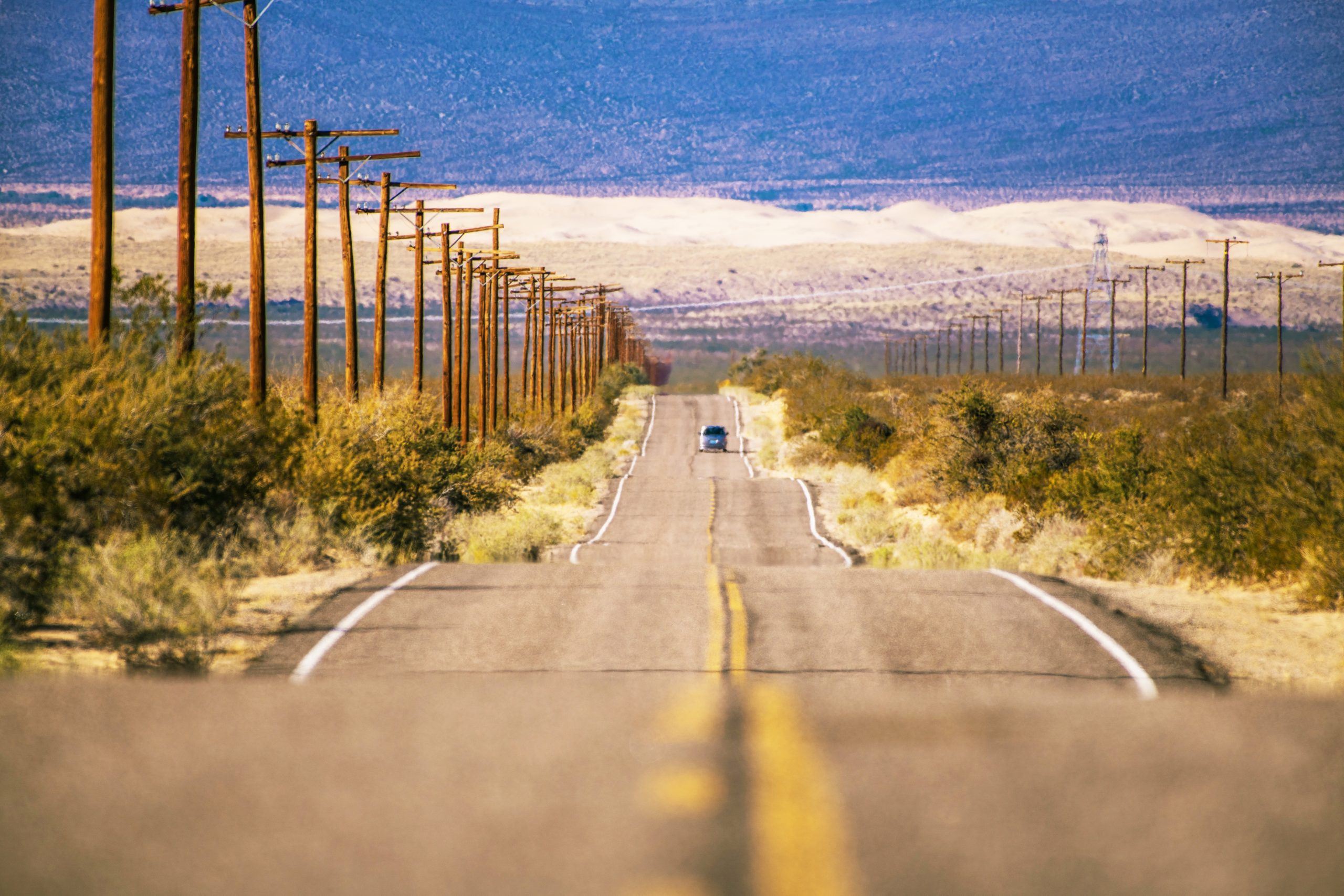 American road trip car driving desert highway at sunset golden hour