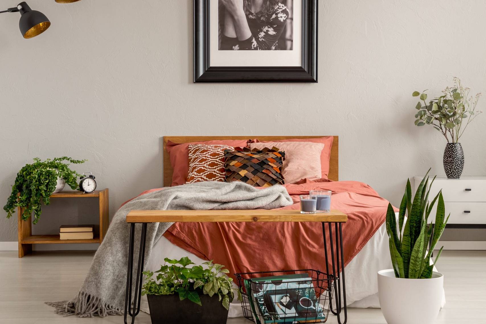 Warm farmhouse bedroom with terracotta bedding, wooden bench and indoor plants