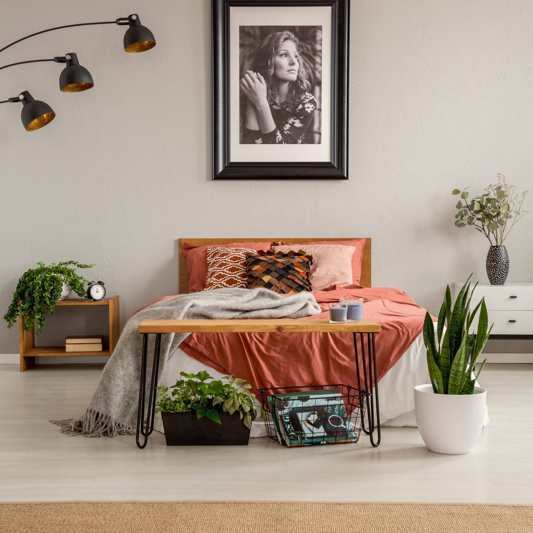 Warm farmhouse bedroom with terracotta bedding, wooden bench and indoor plants