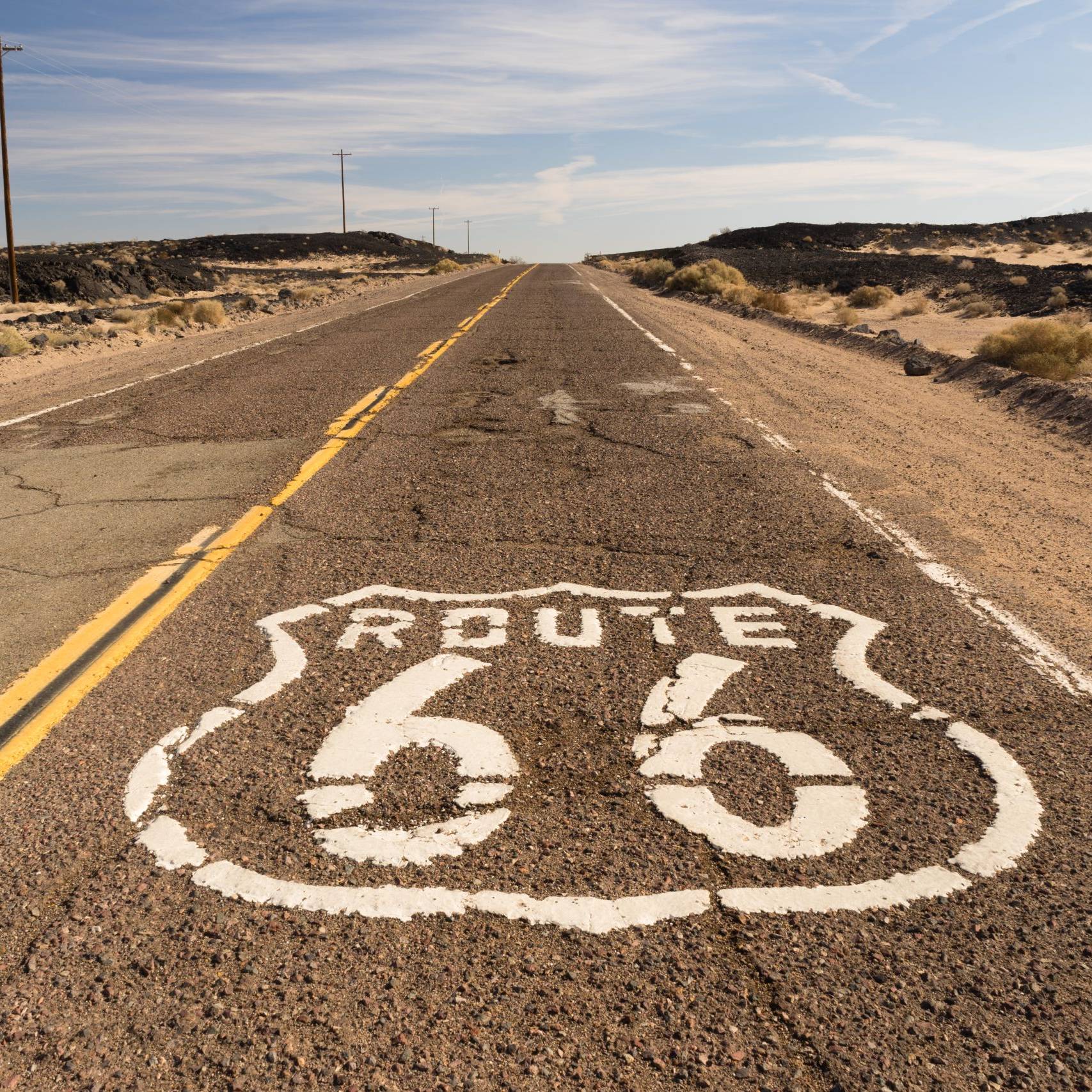 Historic Route 66 shield painted on cracked desert asphalt in the Mojave Desert California