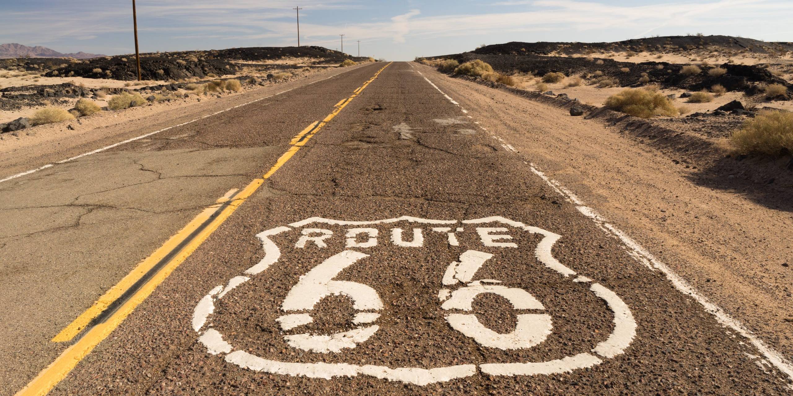 Historic Route 66 shield painted on cracked desert asphalt in the Mojave Desert California