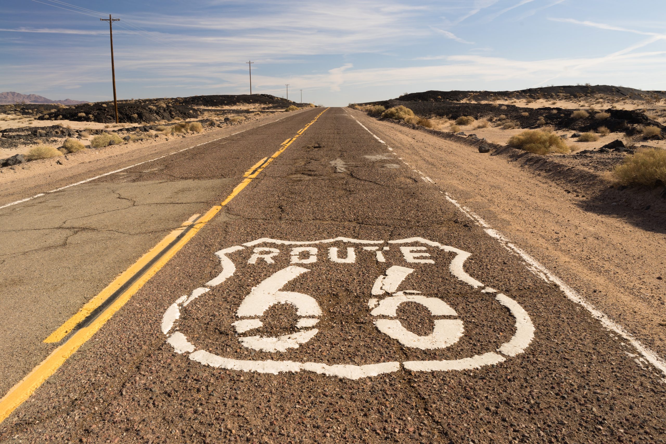Historic Route 66 shield painted on cracked desert asphalt in the Mojave Desert California