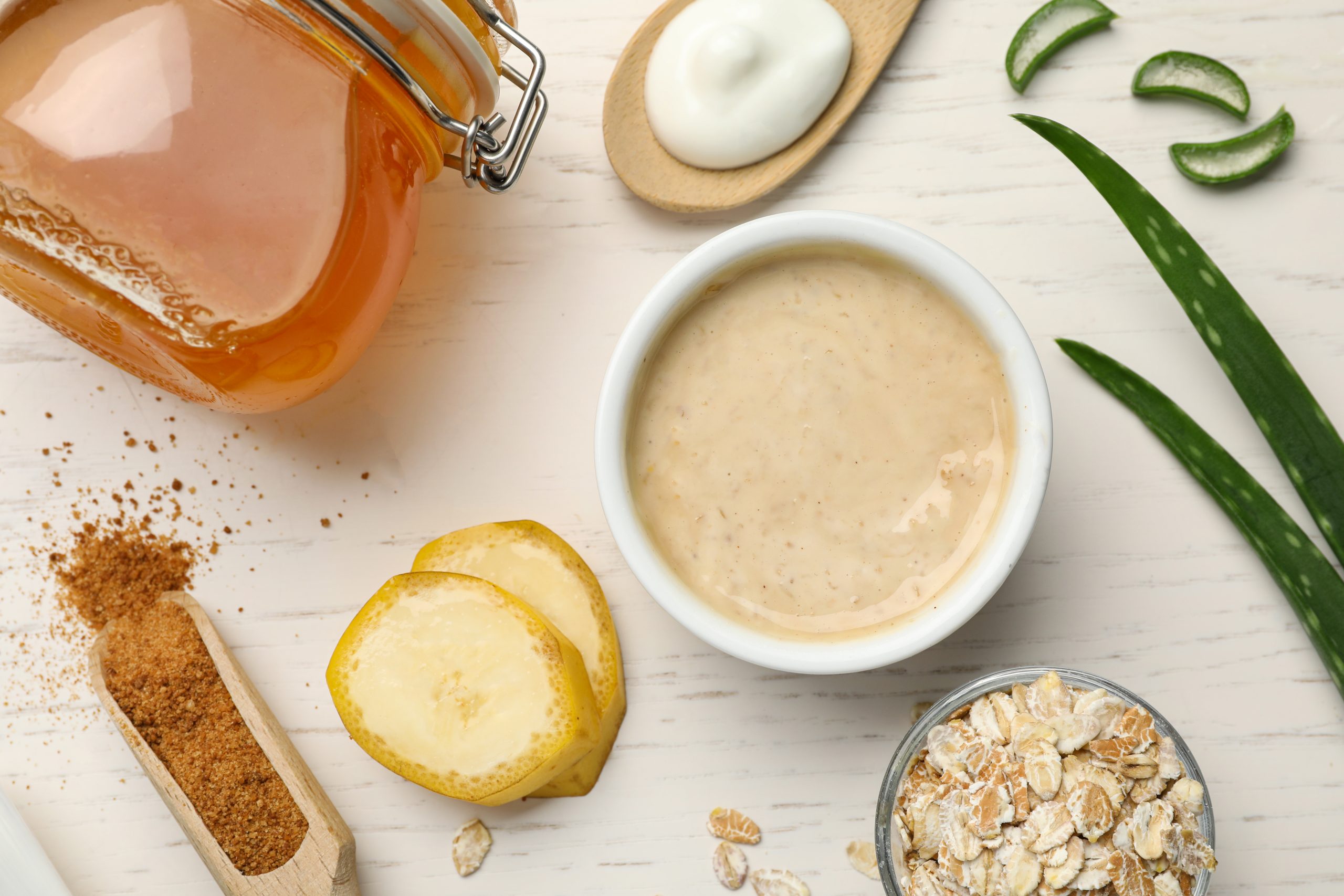 Natural skin care ingredients and handmade face mask on white wooden background, flat lay