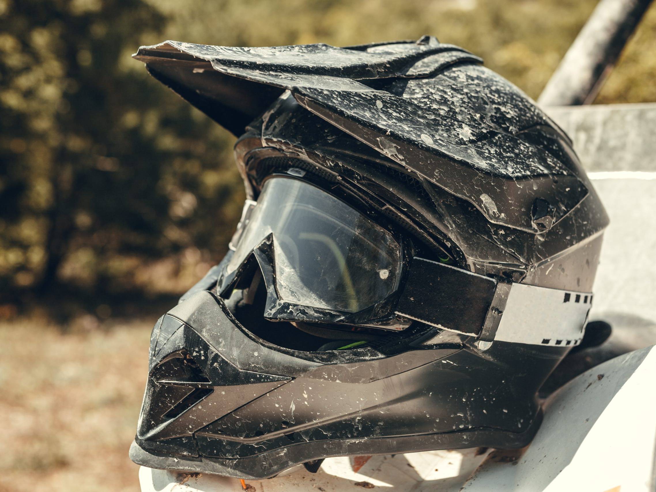 Muddy black off-road adventure helmet resting on ATV — lightweight helmet for road trips