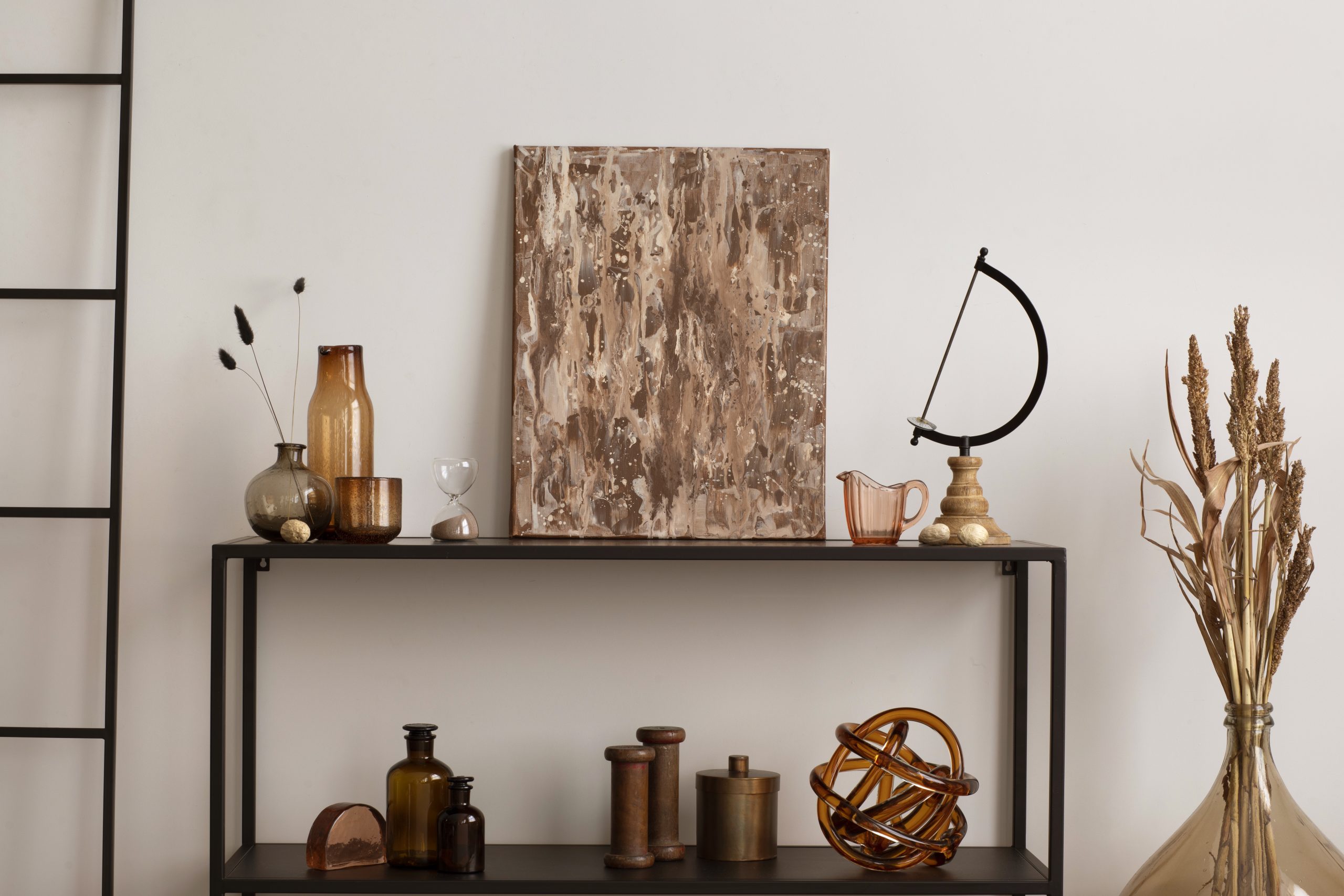 Quiet luxury americana shelf styling with brown abstract painting, amber glass vases and globe