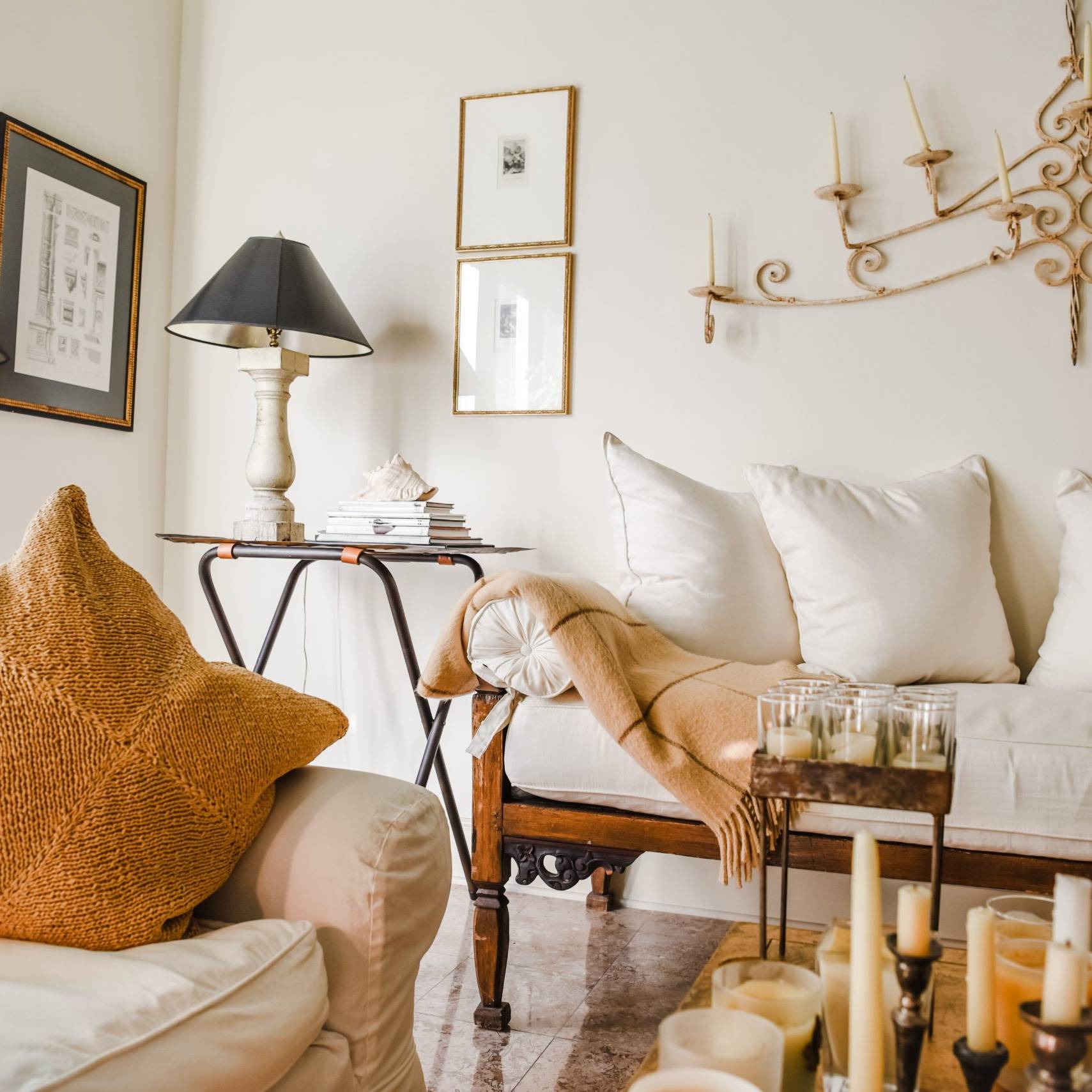 Quiet luxury American living room with white slipcovered sofa, mustard pillow and vintage iron chandelier