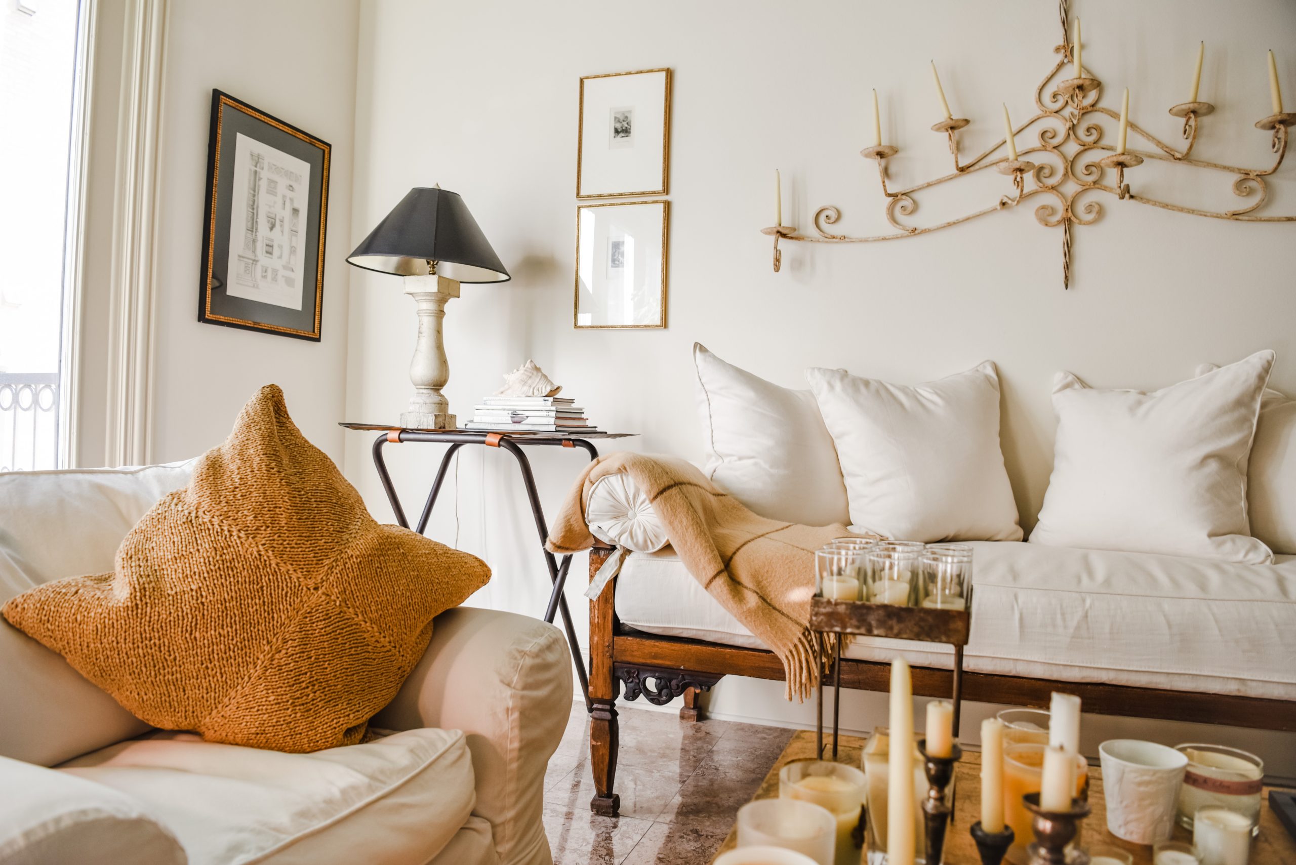 Quiet luxury American living room with white slipcovered sofa, mustard pillow and vintage iron chandelier