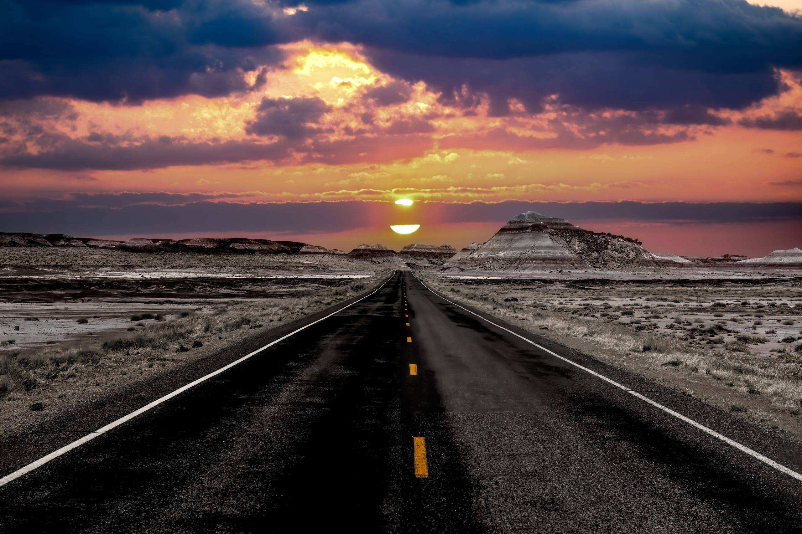 Dramatic sunset over a straight desert highway along Route 66 through the Petrified Forest