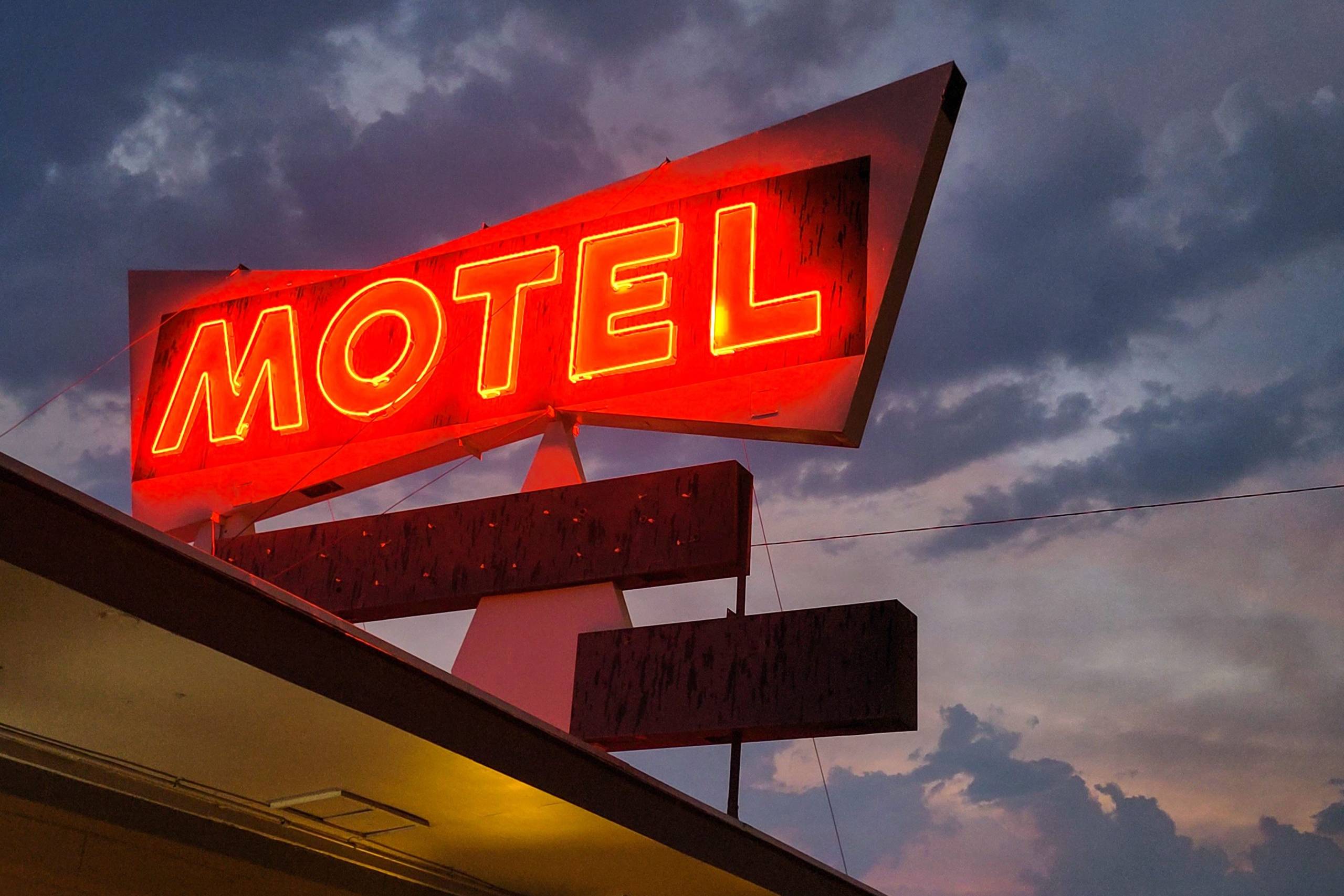 Vintage red neon motel sign glowing against a dramatic dusk sky along Route 66
